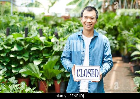 Eccitato giovane uomo che chiude il centro di giardinaggio dopo grande vendita Foto Stock