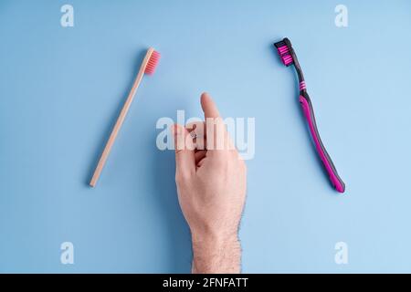 Scegliete tra uno spazzolino in plastica e uno spazzolino in bambù ecologico. Tendenze ecologiche a livello mondiale. Foto Stock