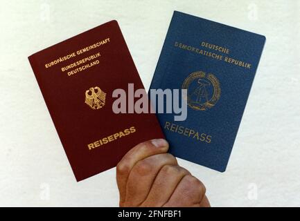 Una mano tiene il passaporto rosso della Repubblica federale di Germania a sinistra e il passaporto della Repubblica democratica tedesca a destra. [traduzione automatizzata] Foto Stock