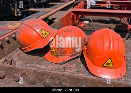 Tre cappelli rigidi arancioni con il logo a doppia freccia della British Rail, Loughborough, UK Foto Stock