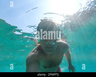 Foto subacquee di un giovane uomo attivo a nuotare in acqua del mare turchese Foto Stock