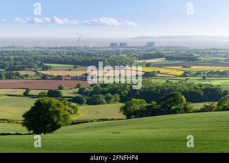 Una soleggiata vista di primavera mattina dai piedi delle colline di Quantock sulla campagna e la centrale elettrica di Hinkley Point sulla riva del canale di Bristol, Somerset, Inghilterra. Foto Stock