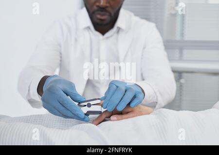 Giovane medico africano in guanti protettivi che si prende cura del suo paziente in ospedale Foto Stock