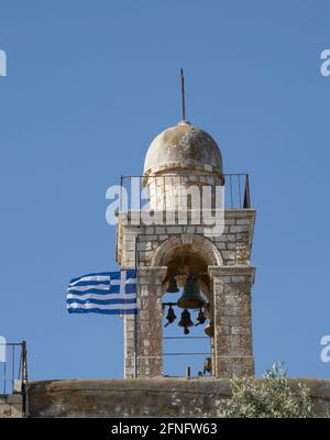 Gerusalemme, Israele - 6 maggio 2021: Il campanile del monastero di Mar Elias, accanto alla bandiera greca. Foto Stock