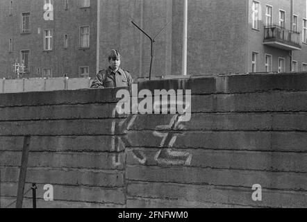 Berlino-Città / GDR / 20.3.1980 Bernauer Strasse in matrimonio. Le vecchie pietre di parete sono sostituite da elementi a L in calcestruzzo liscio. La giovane guardia di frontiera si trova lì per sorvegliare i lavoratori edili. Per impedire loro di fuggire in Occidente. Sul lato ovest qualcuno ha scritto -KZ- sul muro. Dietro il muro si trova Berlin-Mitte. // DDR / Muro / distretti / Stasi / Storia / comunismo [traduzione automatizzata] Foto Stock