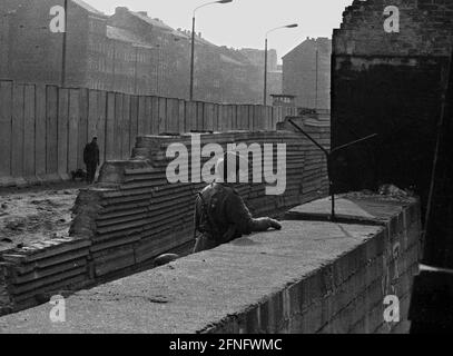 Berlino-Città / GDR / 20.3.1980 Bernauer Strasse in matrimonio. Le vecchie pietre di parete sono sostituite da elementi a L in calcestruzzo liscio. La giovane guardia di frontiera si trova lì per sorvegliare i lavoratori edili. Per impedire loro di fuggire in Occidente. // DDR / Muro / distretti / Soldato / Storia / comunismo [traduzione automatizzata] Foto Stock