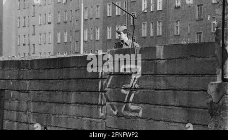 Berlino-Città / GDR / 20.3.1980 Bernauer Strasse in matrimonio. Le vecchie pietre di parete sono sostituite da elementi a L in calcestruzzo liscio. La giovane guardia di frontiera si trova lì per sorvegliare i lavoratori edili. Per impedire loro di fuggire in Occidente. Sul lato ovest qualcuno ha scritto -KZ- sul muro. Dietro il muro si trova Berlin-Mitte. // DDR / Muro / distretti / Stasi / Storia / comunismo [traduzione automatizzata] Foto Stock