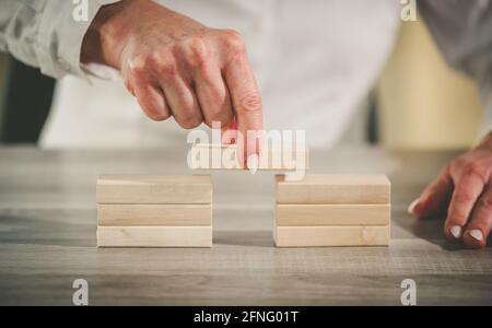 Mano femmina costruzione di un ponte con blocchi di legno; concetto di associazione Foto Stock