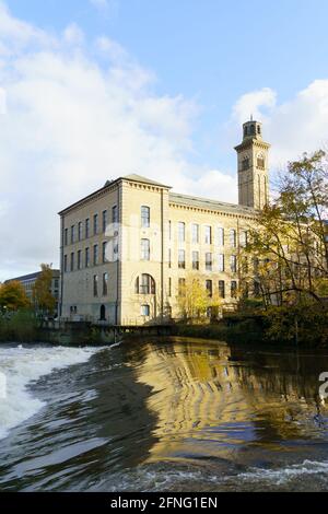 Vista del Salts Mill (precedentemente un impianto tessile) costruito nel 1853, con il fiume Aire Weir in primo piano, Shipley, West Yorkshire, Regno Unito. Foto Stock