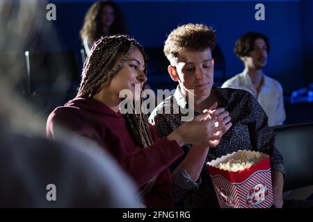 Giovane coppia che mangia popcorn mentre guarda un film al cinema. Foto Stock
