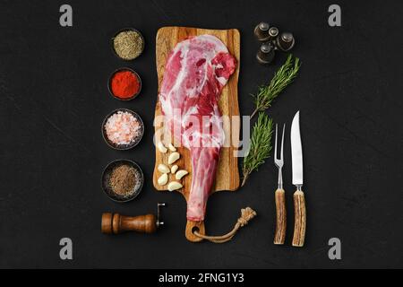 Spalla di agnello sbucciata cruda pronta per la cottura su fondo nero Foto Stock