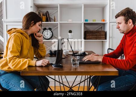 Giovane coppia che lavora a casa nella stessa stanza. Foto Stock