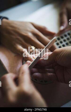 Dall'alto di raccolto faceless manicurista limatura chiodi di irriconoscibile cliente con file durante la procedura in salone di bellezza Foto Stock