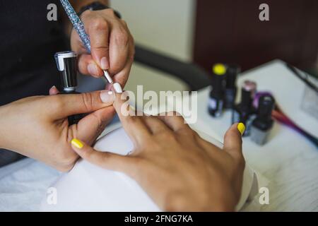 Dall'alto di raccolto manicurista irriconoscibile facendo arte del chiodo per cliente femminile in salone di bellezza alla luce del giorno Foto Stock