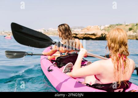 Viaggiatori con vista posteriore con pale galleggianti su acque turchesi vicino La costa rocciosa in giornata di sole a Malaga Spagna Foto Stock