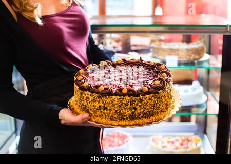 Pasticceria femmina presentando il vassoio della torta nel forno o pasticceria Foto Stock