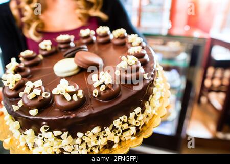 Pasticceria femmina presentando il vassoio della torta nel forno o pasticceria Foto Stock