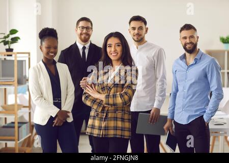Donna d'affari sorridente con un gruppo di affari di squadra diverso in ufficio Foto Stock
