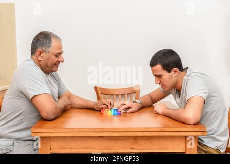 Figlio adolescente e padre anziano seduto a casa e giocando con il giocattolo flessibile il pop fidget. Poppit nuovo fidget giocattolo, popolare con i bambini, e le persone con esigenze speciali, li aiutano a concentrarsi. Foto Stock