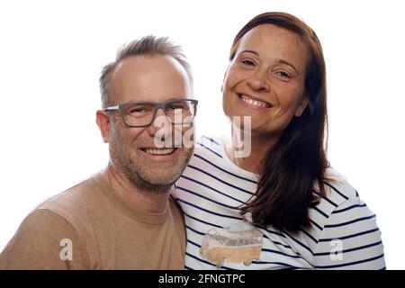 Sorridente amichevole affettuosa coppia di mezza età in posa con le braccia intorno l'uno all'altro guardando la telecamera isolata in bianco Foto Stock