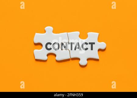 Pezzi di puzzle collegati con la parola contatto. Concetto di comunicazione, cooperazione o interazione. Foto Stock