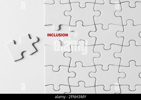 Concetto di inclusione, integrazione e togetherness. La parola inclusione scritta su pezzo di puzzle mancante su sfondo bianco. Foto Stock