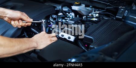 meccanico lavoro con chiave su motore veicolo in assistenza auto. manutenzione e riparazione. spazio copia banner Foto Stock