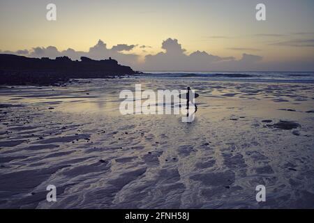 Surfer sulla spiaggia di Porthmeor al tramonto Foto Stock