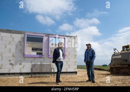 Nordstrandischmoor, Germania. 17 maggio 2021. Jan Philipp Albrecht (l - Bündnis 90/Die Grünen), Ministro dell'ambiente di Schleswig-Holstein, parla con nomme Kruse nel cantiere. Albrecht presentò Kruse e la sua famiglia all'Hallig Nordstrandischmoor con una sovvenzione per il Norderwarft. Attualmente è in fase di sviluppo nel primo tumulo di abitazioni controllate dal clima del mondo. Credit: Frank Molter/dpa/Alamy Live News Foto Stock