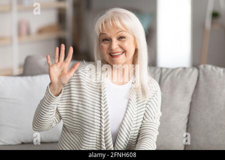 Donna matura che sventolava con la macchina fotografica e sorride Foto Stock