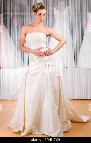 Donna cerca su abiti da sposa o abito nuziale in wedding fashion store Foto Stock