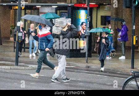 PIC mostra: Pioggia pesante e tuono infrangeva la giornata a Londra acquirenti e lunchers ad Angel Islington catturati sotto la pioggia. Giornale consegna uomo Foto Stock