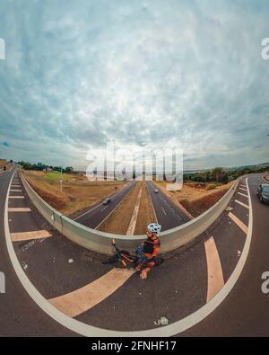 Uomo nero con casco e occhiali che cavalcano una bicicletta sulla strada. Foto Stock