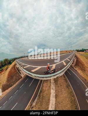 Uomo nero con casco e occhiali che cavalcano una bicicletta sulla strada. Foto Stock