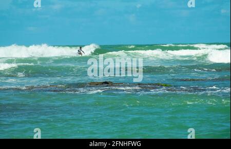 Un uomo che surfing nella barriera corallina si rompe Foto Stock