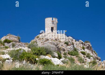 Scopello, Trapani, Sicilia, Italia. Vista su una collina rocciosa fino alla Torre Bennistra, una torre medievale restaurata, ora mirador in cima alla scogliera. Foto Stock