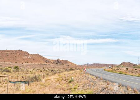 I veicoli sono visibili sulla strada N1 tra Richmond e Three Sisters nel nord di Cape Karoo. Una croce e la parola vita in Afrikaans sono visibili agai Foto Stock