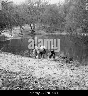 1969, storico, foresta di Epping, un padre con bambini piccoli con reti da pesca a Baldwin Pond, Epping, Essex, Inghilterra, Regno Unito. Foto Stock