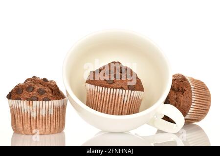 Tre muffin al cioccolato e una tazza bianca su sfondo bianco. Foto Stock