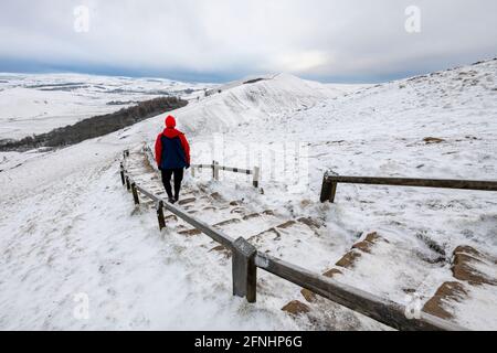 Un escursionista in inverno a piedi verso Rushup Edge da MAM Tor, Peak District, Derbyshire Foto Stock