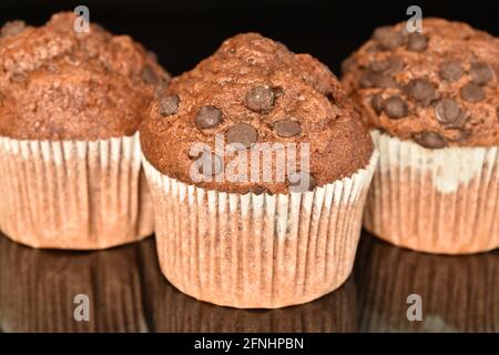 Tre deliziosi muffin al cioccolato, primo piano, su sfondo nero. Foto Stock