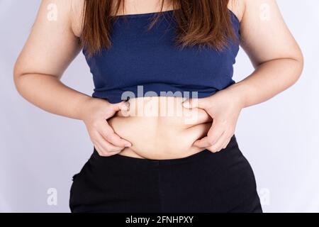 Donna grassa che tiene eccessivamente pancia grassa isolato sfondo grigio. Foto Stock