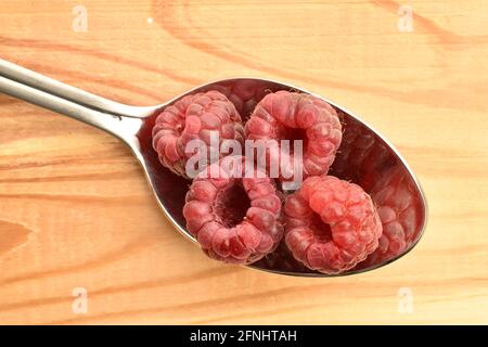 Diversi lamponi rossi neri organici in un cucchiaio di metallo, closeup, su un tavolo di legno, vista dall'alto. Foto Stock