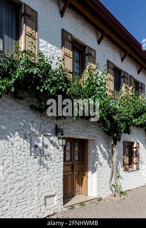 Primo piano vista della tradizionale casa vecchia con persiane in legno e fiori nella famosa città egea chiamata 'Sigacik'. È un villaggio di Seferihisar Foto Stock