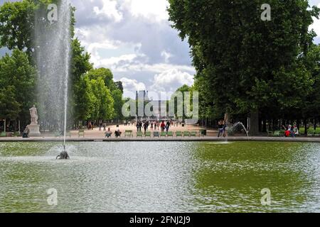 Parigi, Francia, 22 giugno: Parigini e visitatori passeggiano per lo stagno nel Giardino delle Tuileries sullo sfondo del Louvre in una giornata di sole Foto Stock