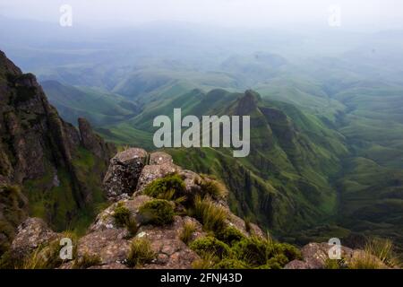 Vista dalle alte cime dei Monti Drakensberg al confine tra il Sud Africa e il Lesotho, con le verdi colline e le montagne sottostanti Foto Stock