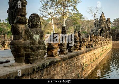 Fila di asuras (demoni) e South Gate, Angkor Thom, il Parco Archeologico di Angkor, Siem Reap, Cambogia Foto Stock