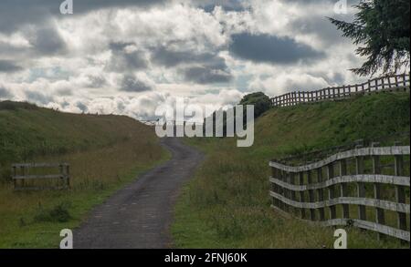 Vista del ciclista di avvicinamento lungo la curva di una vecchia ferrovia ora un diritto pubblico di strada con cielo impressionante in Durham Dales Foto Stock