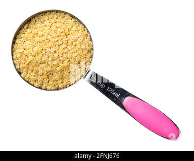 vista dall'alto della pastina stellina non cotte nel foro della tazza di misurazione su sfondo bianco Foto Stock