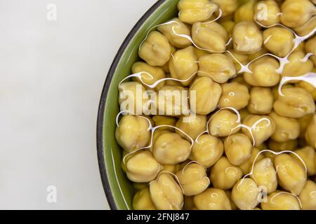 Ceci imbevuti in acqua, in ciotola, su tavola di marmo. Concetto di alimentazione sana, veganismo, vegetarianismo, sostituzione di carne e uova. Preparare i ceci b Foto Stock